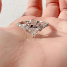 a person holding an engagement ring in their hand with the diamond on it's side