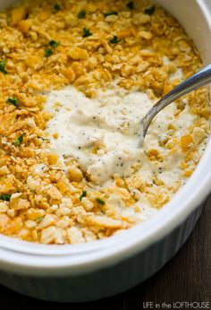 a white bowl filled with food on top of a wooden table next to a spoon