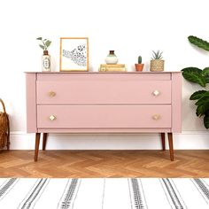 a pink dresser sitting next to a potted plant on top of a hard wood floor