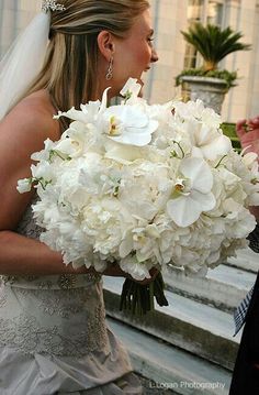 a bride holding a bouquet of white flowers