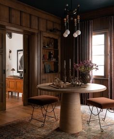 a dining room table with two chairs and a chandelier hanging from the ceiling