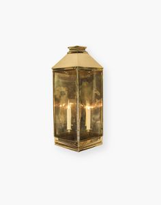 an old fashioned brass wall light with two candles on the front and back of it