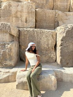 a woman sitting on top of a rock formation next to some large stone blocks in the desert