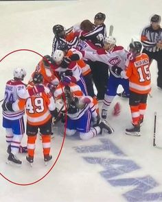 a group of hockey players huddled together in the middle of an ice rink with referee looking on