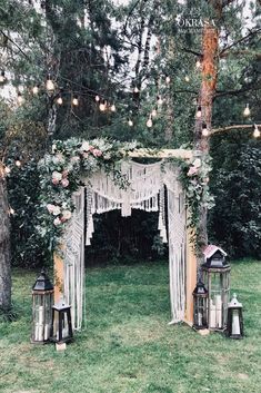 an outdoor wedding ceremony set up in the grass with lanterns and flowers hanging from the trees