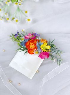 a bouquet of colorful flowers sitting on top of a white sheet