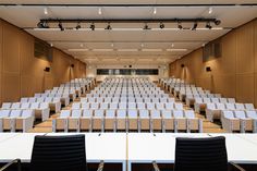 an empty lecture hall with rows of white tables and chairs in front of the podiums