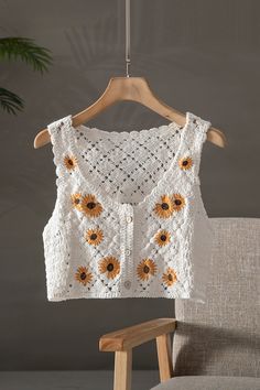 a crocheted sunflower sweater hanging on a hanger next to a chair