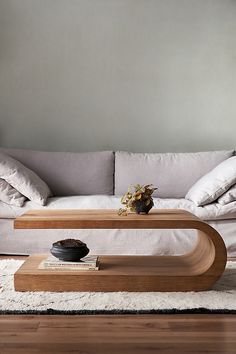 a living room with a couch, coffee table and pillows on the floor in front of it