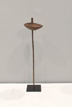 a metal object with a wooden stick sticking out of it's side on a white surface