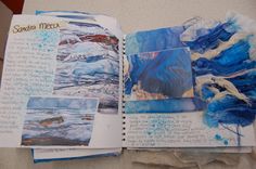 an open book with blue and white papers on it, including watercolors in the pages