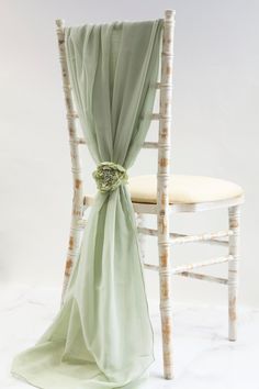 a chair with a green sash and flower on the back of it's seat