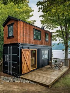 a small house made out of shipping containers on a wooden deck next to the water