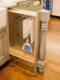 an open cabinet in the middle of a kitchen with cleaning supplies on top of it