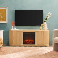 a living room with a fireplace and television on the wall, in front of a couch