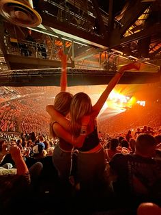 two women hugging each other in front of an audience at a concert or show with bright lights