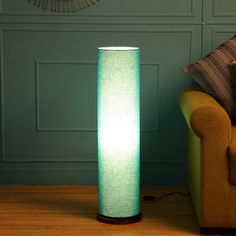 a green lamp sitting on top of a wooden floor next to a couch in a living room