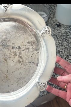 a person is holding a silver plate in their hand