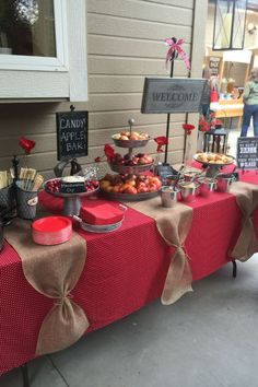 a red table topped with lots of food and desserts on top of it's sides