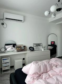 a bedroom with white walls and pink comforter on top of the bed, along with an air conditioner hanging from the ceiling