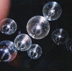 several shiny disco balls are being held by someone's hand