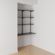 an empty room with some shelves in the corner and wood flooring on the other side