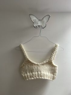 a knitted bra hanging on a white wall with a butterfly decoration above the bra