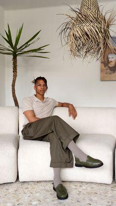 a man sitting on top of a white couch next to a potted palm tree