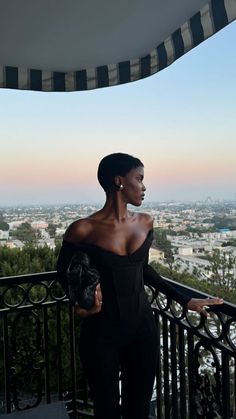 a woman standing on top of a balcony next to a black and white awning