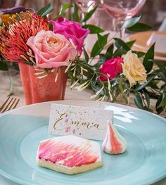 a plate with some cookies on it next to a flower vase and place card holder