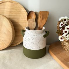 wooden utensils are in a green and white container next to other kitchen accessories