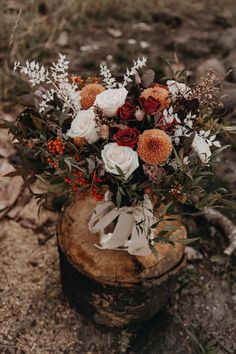 a bouquet of flowers sitting on top of a tree stump