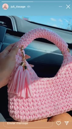 a pink purse sitting on top of a car dashboard next to a person holding it