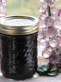 a glass jar filled with black liquid next to flowers