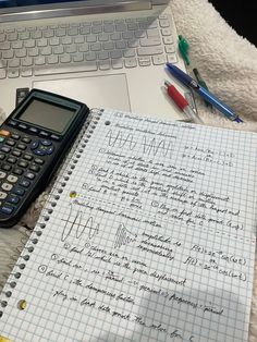 a calculator sitting on top of a notebook next to an open laptop computer