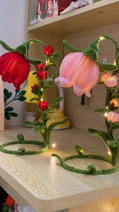 some flowers are sitting on a table with string lights around them and in front of a book shelf