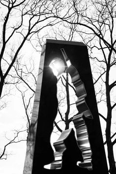 a black and white photo of a street light with trees in the backround