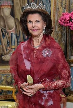 an older woman wearing a tiara and holding a piece of fruit in her hand