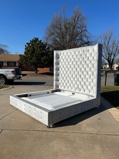 a white bed sitting in the middle of a driveway