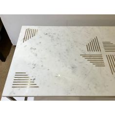 a white marble table with gold lines on the top and bottom, sitting in a room