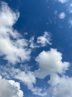 the airplane is flying high in the blue sky with white clouds above it and below