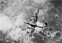 an old airplane flying through the sky over land and clouds in black and white photo