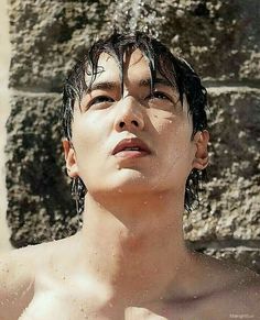 a man with wet hair standing in front of a brick wall