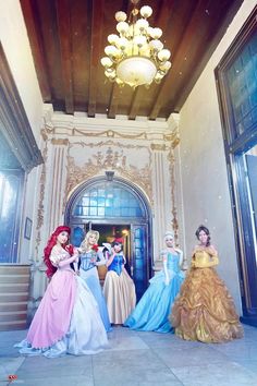 four princesses are standing in front of the entrance to an ornate building with chandelier