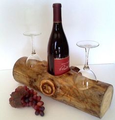 a bottle of wine sitting on top of a piece of wood next to two glasses