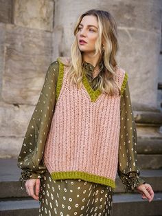 a woman standing in front of a building wearing a sweater and pants with polka dots