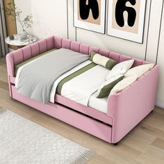 a pink day bed sitting in front of two pictures on the wall next to a rug