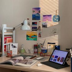 a laptop computer sitting on top of a wooden desk next to a lamp and books