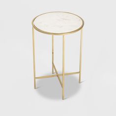 a white marble top side table with gold metal legs and a round base, on a grey background