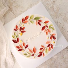 a cake decorated with leaves and the words thank you on it is sitting on top of a card